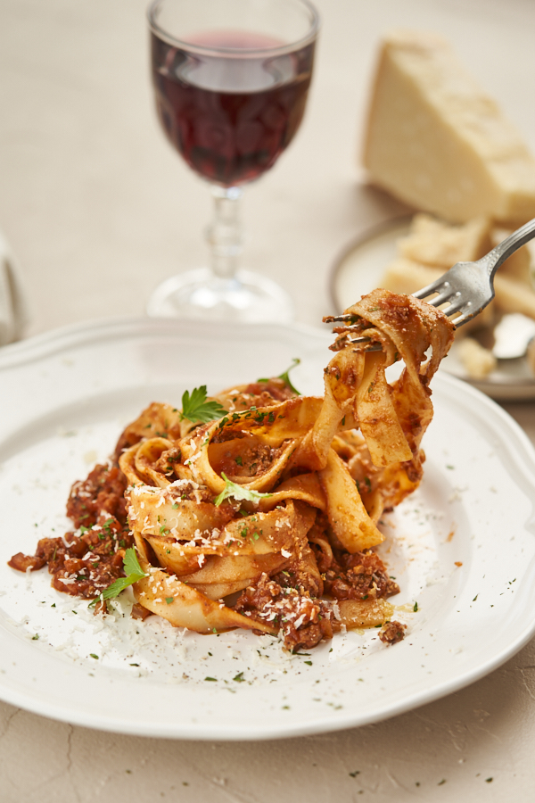 Bolognese Pasta auf einem Teller mit Wein und Parmesan