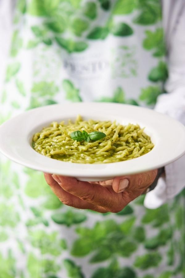 Personne tenant un plat de Pesto Genovese avec des pâtes