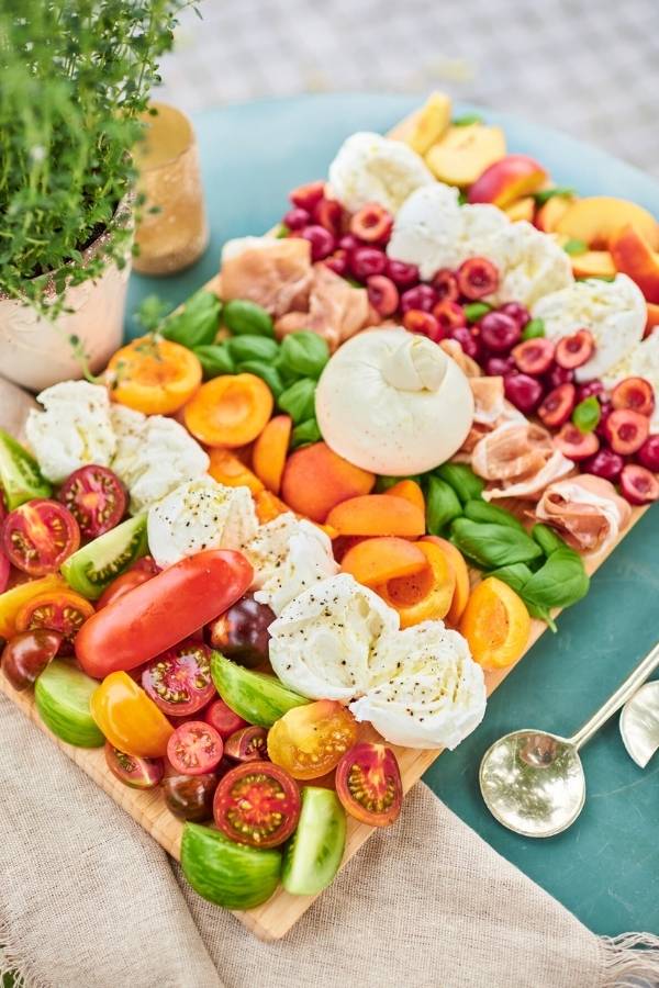 Plateau d'antipasti coloré avec cerises, abricots, tomates, basilic et mozzarella