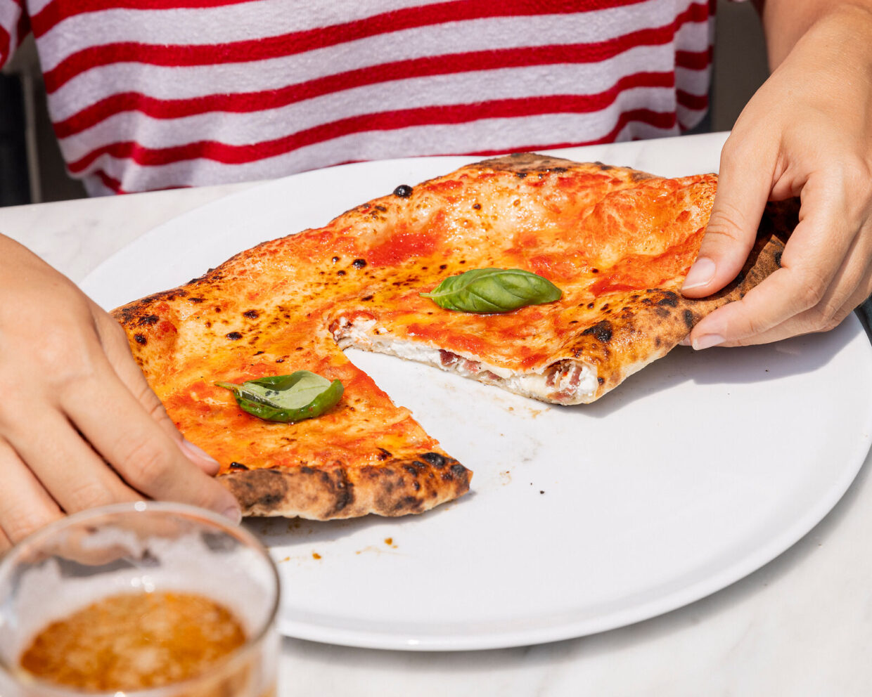 zwei Hände reißen eine frische neapolitanische Calzone auseinander