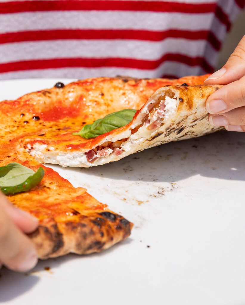 zu sehen ist eine frische Calzone im Querschnitt, die Füllung ist deutlich zu erkennen: Ricotta, Parmesan und Salami