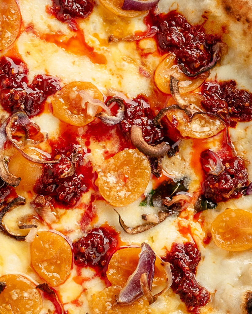 Nahaufnahme des saftigen Belags zeigt die leicht geschmolzene Nduja auf der Pizza