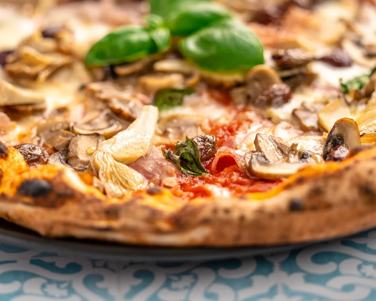 nahaufnahme einer Pizza Capricciosa mit Schinken, Artischokenherzen, Champignons und Oliven