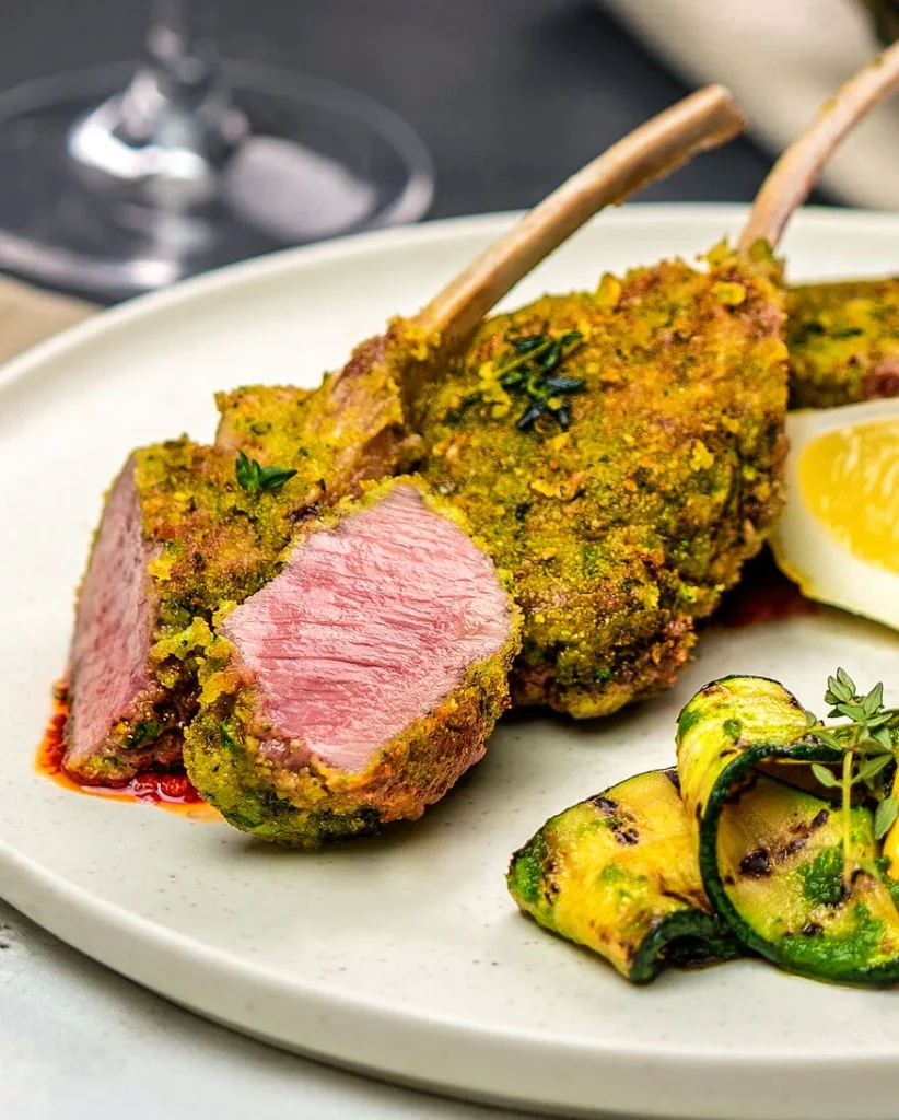 Nahaufnahme eines angeschnittenen Lammkoteletts. Man sieht die Struktur des Fleischs und die zartrosa Farbe