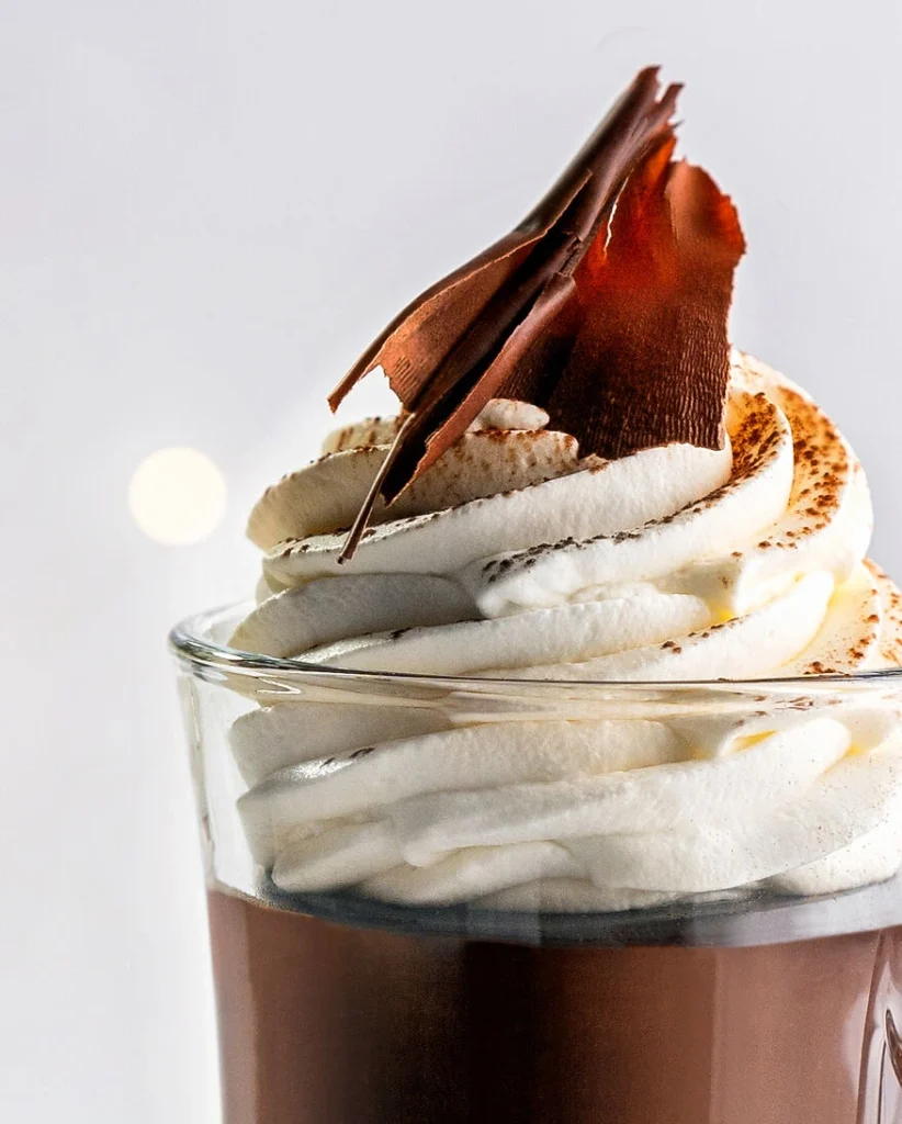 Nahaufnahme der Sahnehaube mit Kakaogarnitur auf der heißen Schokolade