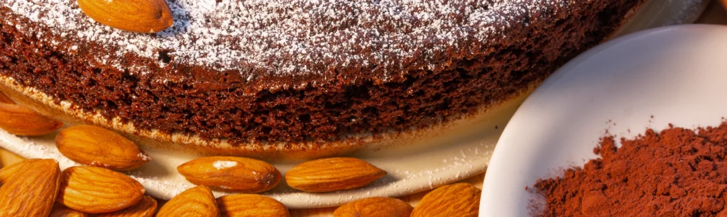 Nahaufnahme einer Torta Caprese umringt von ganzen Mandeln