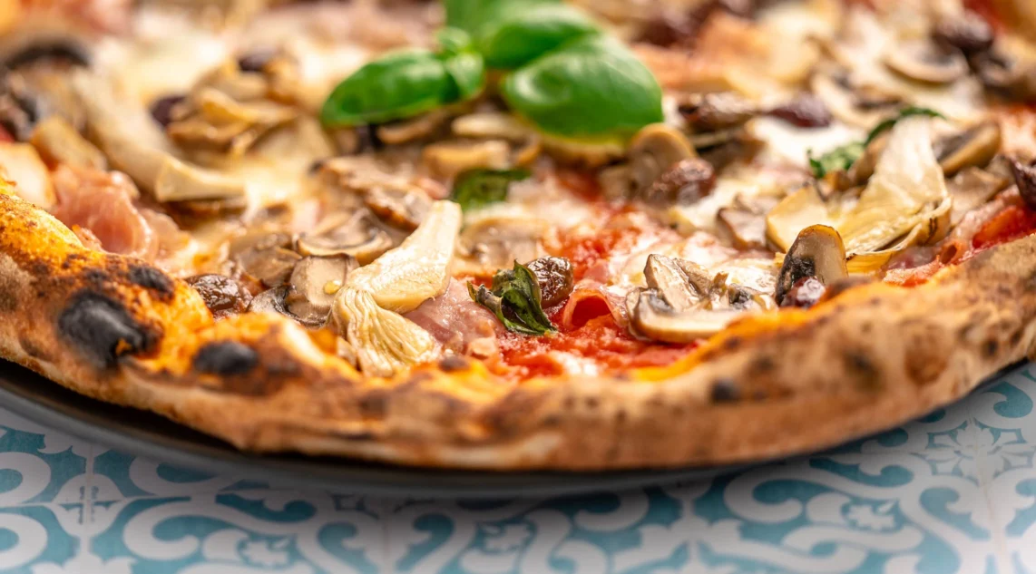 nahaufnahme einer Pizza Capricciosa mit Schinken, Artischokenherzen, Champignons und Oliven