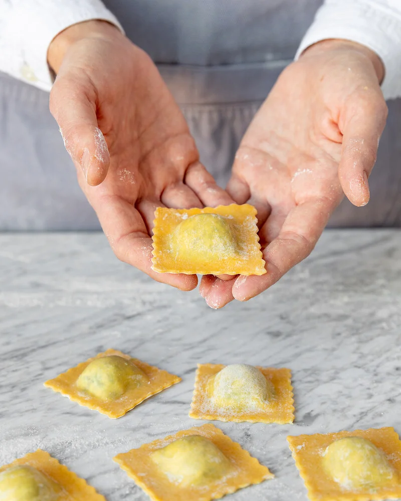 zwei Hände präsentieren eine Ravioli